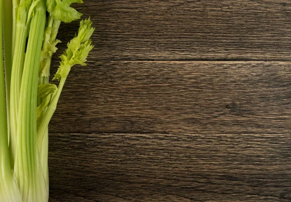 Ham yeşil kereviz ahşap arka plan üstten görünüm üzerinde takip ediyor. Eski ahşap rustik masa metin veya boşaltmak için yer ile taze organik sebze