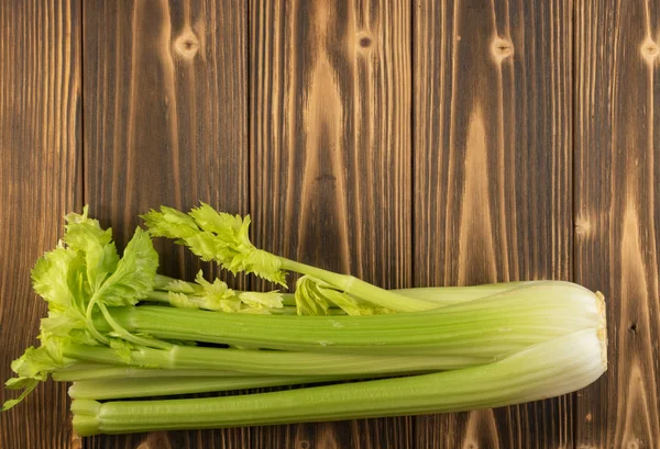 Ham yeşil kereviz ahşap arka plan üstten görünüm üzerinde takip ediyor. Eski ahşap rustik masa metin veya boşaltmak için yer ile taze organik sebze
