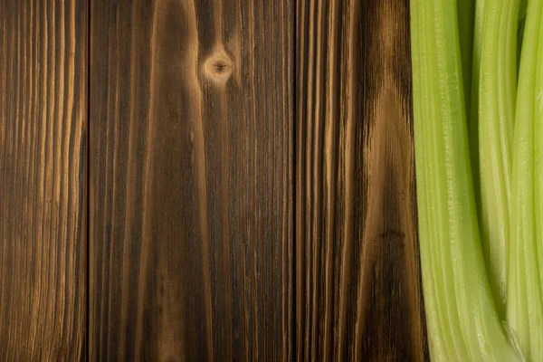 Ham yeşil kereviz ahşap arka plan üstten görünüm üzerinde takip ediyor. Eski ahşap rustik masa metin veya boşaltmak için yer ile taze organik sebze