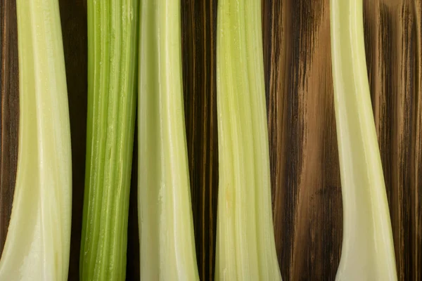 Ham yeşil kereviz ahşap arka plan üstten görünüm üzerinde takip ediyor. Eski ahşap rustik masa metin veya boşaltmak için yer ile taze organik sebze