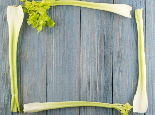 Ham yeşil kereviz ahşap arka plan üstten görünüm üzerinde takip ediyor. Taze organik kare sebze çerçeve boşaltmak eski ahşap rustik tablo