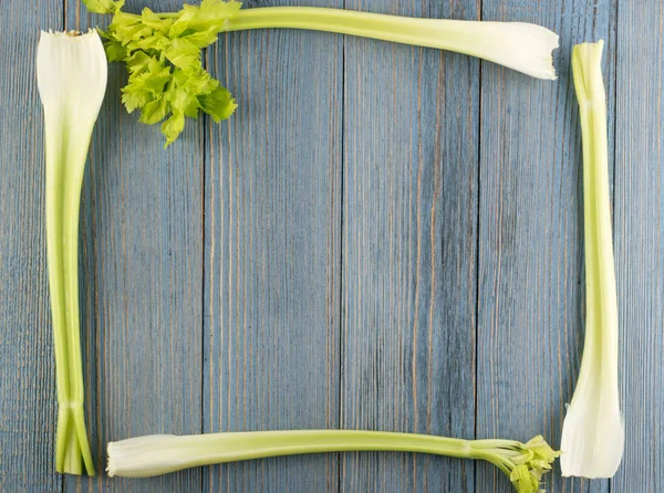 Ham yeşil kereviz ahşap arka plan üstten görünüm üzerinde takip ediyor. Taze organik kare sebze çerçeve boşaltmak eski ahşap rustik tablo