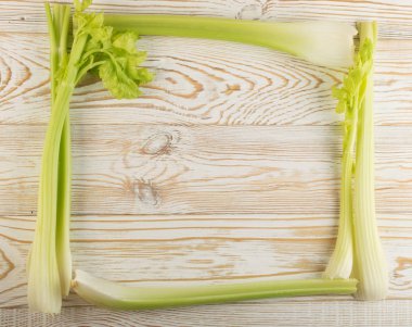 Ham yeşil kereviz ahşap arka plan üstten görünüm üzerinde takip ediyor. Taze organik kare sebze çerçeve boşaltmak eski ahşap rustik tablo