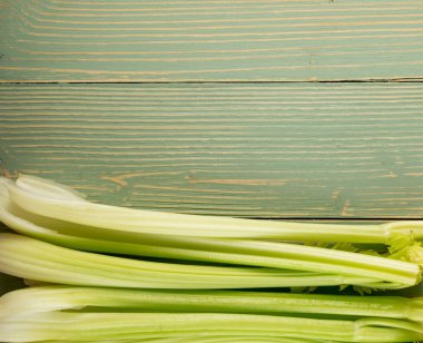 Ham yeşil kereviz ahşap arka plan üstten görünüm üzerinde takip ediyor. Eski ahşap rustik masa metin veya boşaltmak için yer ile taze organik sebze