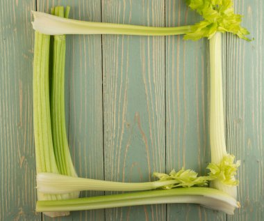 Ham yeşil kereviz ahşap arka plan üstten görünüm üzerinde takip ediyor. Taze organik kare sebze çerçeve boşaltmak eski ahşap rustik tablo