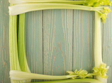 Ham yeşil kereviz ahşap arka plan üstten görünüm üzerinde takip ediyor. Taze organik kare sebze çerçeve boşaltmak eski ahşap rustik tablo