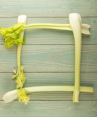 Ham yeşil kereviz ahşap arka plan üstten görünüm üzerinde takip ediyor. Taze organik kare sebze çerçeve boşaltmak eski ahşap rustik tablo