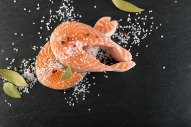 Doğal siyah arka plan üzerine çiğ somon Steak dilim. Kalın parça taze kırmızı balık ya da tuz ve baharatlar ile alabalık