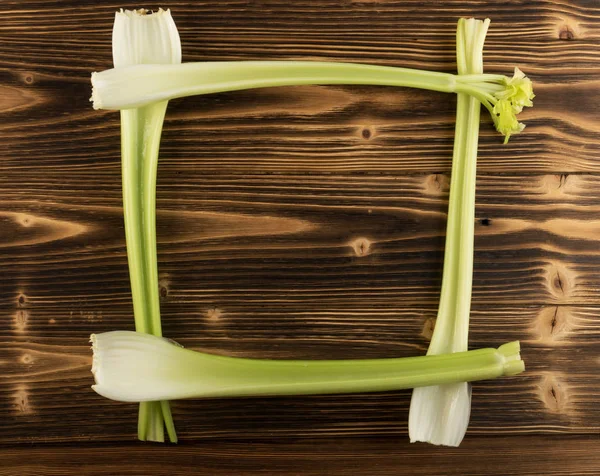 Ham yeşil kereviz ahşap arka plan üstten görünüm üzerinde takip ediyor. Taze organik kare sebze çerçeve boşaltmak eski ahşap rustik tablo