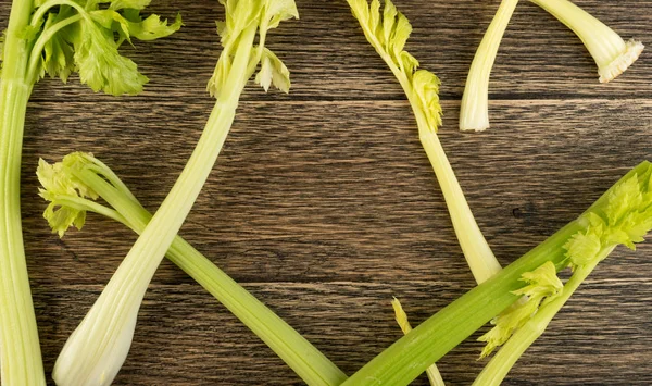 Ham yeşil kereviz ahşap arka plan üstten görünüm üzerinde takip ediyor. Eski ahşap rustik masa metin veya boşaltmak için yer ile taze organik sebze