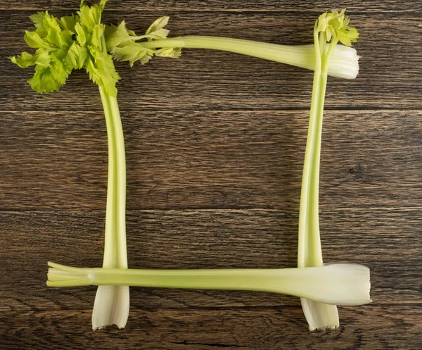 Ham yeşil kereviz ahşap arka plan üstten görünüm üzerinde takip ediyor. Taze organik kare sebze çerçeve boşaltmak eski ahşap rustik tablo