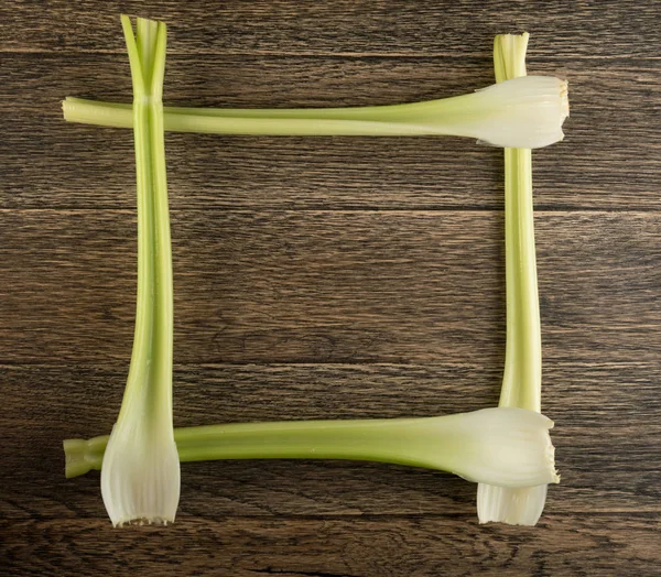 Ham yeşil kereviz ahşap arka plan üstten görünüm üzerinde takip ediyor. Taze organik kare sebze çerçeve boşaltmak eski ahşap rustik tablo