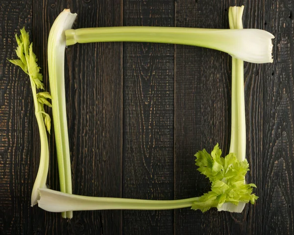 Ham yeşil kereviz ahşap arka plan üstten görünüm üzerinde takip ediyor. Taze organik kare sebze çerçeve boşaltmak eski ahşap rustik tablo