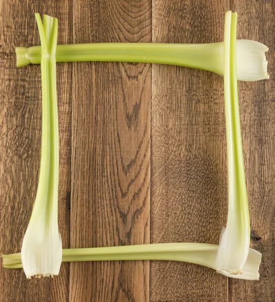 Ham yeşil kereviz ahşap arka plan üstten görünüm üzerinde takip ediyor. Taze organik kare sebze çerçeve boşaltmak eski ahşap rustik tablo