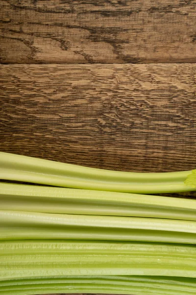Ham yeşil kereviz ahşap arka plan üstten görünüm üzerinde takip ediyor. Eski ahşap rustik masa metin veya boşaltmak için yer ile taze organik sebze