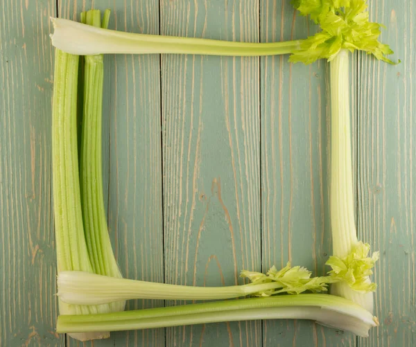 Ham yeşil kereviz ahşap arka plan üstten görünüm üzerinde takip ediyor. Taze organik kare sebze çerçeve boşaltmak eski ahşap rustik tablo