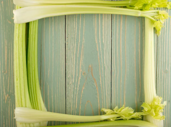 Ham yeşil kereviz ahşap arka plan üstten görünüm üzerinde takip ediyor. Taze organik kare sebze çerçeve boşaltmak eski ahşap rustik tablo