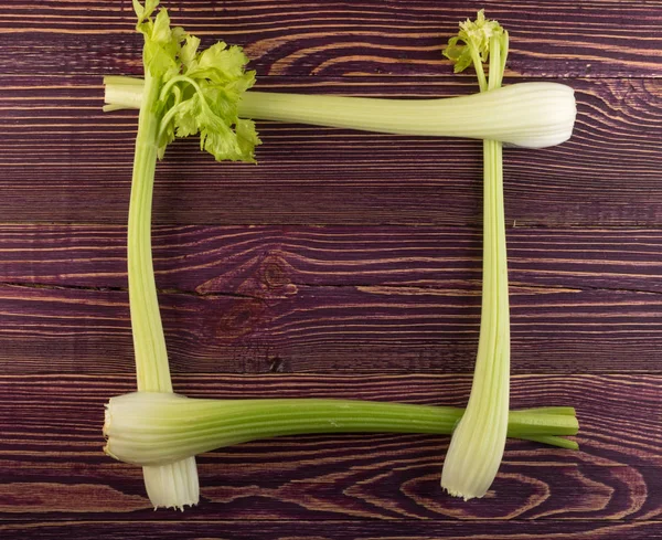 Ham yeşil kereviz ahşap arka plan üstten görünüm üzerinde takip ediyor. Taze organik kare sebze çerçeve boşaltmak eski ahşap rustik tablo