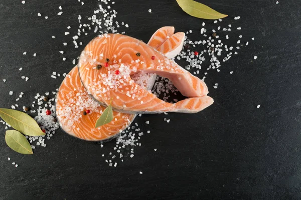 Doğal siyah arka plan üzerine çiğ somon Steak dilim. Kalın parça taze kırmızı balık ya da tuz ve baharatlar ile alabalık