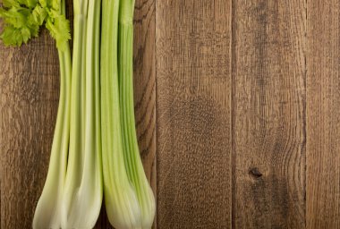 Ham yeşil kereviz ahşap arka plan üstten görünüm üzerinde takip ediyor. Eski ahşap rustik masa metin veya boşaltmak için yer ile taze organik sebze