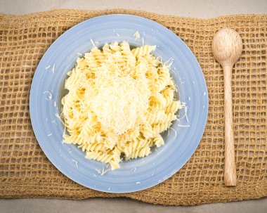 Beyaz arka plan üzerinde izole mavi tabak sıcak Düdük makarna üzerine rendelenmiş peynir yığını. Ev yapımı İtalyan spirale erişte fotoğraf yukarıda ve yan