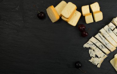 Peygamberli dilimlenmiş Limburger, Herve peynir veya Reblochon ve mavi Gorgonzola, rokfor veya Stilton. Peynir siyah sarı ve mavi peynir üstten görünüm karışımı ile ders taş plaka arka plan