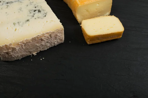 青いゴルゴンゾーラやルブロション エルベ チーズ スライス Limburger のチーズの盛り合わせロック フォール スティルトン 黒に黄色と青のチーズを上面のミックス コースをチーズ石プレート — ストック写真