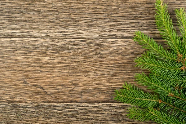木製の背景フラットレイアウトとトップビューにモミの枝とクリスマスの背景 木製のテーブルの上にコピースペースとユリタイドの花のフレームの装飾 新年の挨拶カードのための創造的なクリスマスツリーの境界 — ストック写真