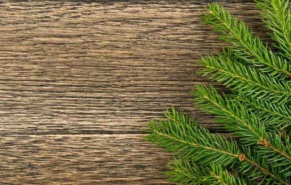 木製の背景フラットレイアウトとトップビューにモミの枝とクリスマスの背景 木製のテーブルの上にコピースペースとユリタイドの花のフレームの装飾 新年の挨拶カードのための創造的なクリスマスツリーの境界 — ストック写真
