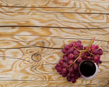 Melez (bitki) ahşap doku arka plan ile kadeh kırmızı şarap ve üzüm. Hafif kurulları ile bir güzel doğal desen ve meyve üstten görünüm