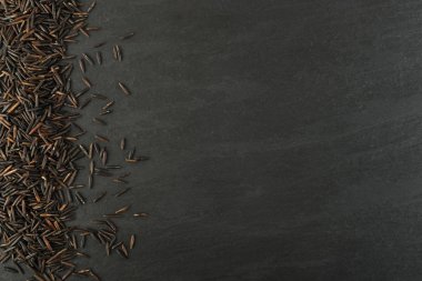 Ham siyah yabani pirinç üzerinde koyu taş arka plan en iyi görünüm düz yatıyordu. Sağlıklı diyet Kanada Bio pirinç tahıl doku TOPVIEW metin veya boşaltmak için yer ile
