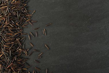 Ham siyah yabani pirinç üzerinde koyu taş arka plan en iyi görünüm düz yatıyordu. Sağlıklı diyet Kanada Bio pirinç tahıl doku TOPVIEW metin veya boşaltmak için yer ile