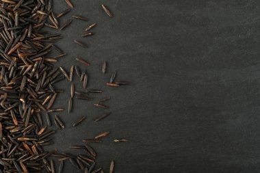 Ham siyah yabani pirinç üzerinde koyu taş arka plan en iyi görünüm düz yatıyordu. Sağlıklı diyet Kanada Bio pirinç tahıl doku TOPVIEW metin veya boşaltmak için yer ile