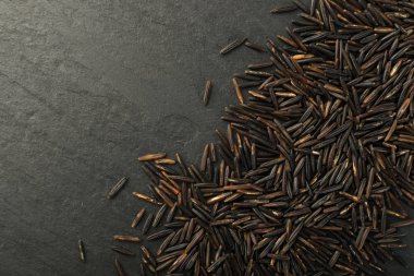 Ham siyah yabani pirinç üzerinde koyu taş arka plan en iyi görünüm düz yatıyordu. Sağlıklı diyet Kanada Bio pirinç tahıl doku TOPVIEW metin veya boşaltmak için yer ile