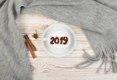 2019 Macchiato ya da gri kareli rustik ahşap zemin üzerine sütlü kapuçino. Ahşap masa üstten görünüm üzerinde Krem Süt köpüğü ile sıcak kahve fincanı