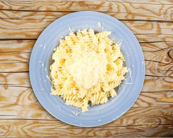 一堆磨碎的干酪放在热 Fusilli 面食上 蓝色盘子上的白色背景 自制意大利 Spirale 面照片从上方和侧面 — 图库照片