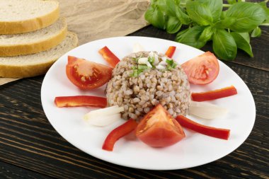 Mükemmel hizmet Buğday lapası rustik zemin üzerine kapatın. Rus kaşa veya pişmiş Pseudocereal Buck buğday yeşil soğan ve dilimlenmiş domates ile dekore edilmiş