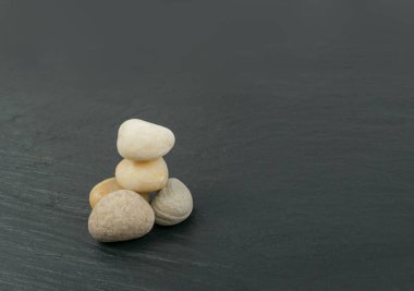 Denge içinde taşlar felsefe meditasyon kavram olarak yığılmış. Siyah taş zemin üzerine beyaz cairns veya çakıl Kulesi