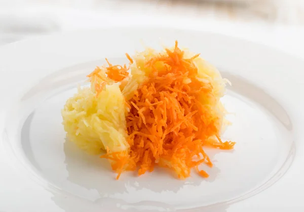 Macro photo of grated carrot and apple on white plate close up. Chopped fruit and vegetable for vegetarian salad