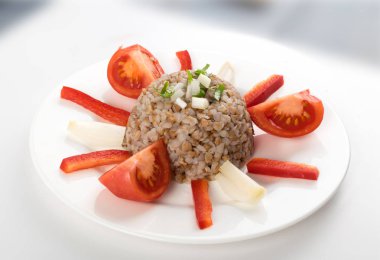 Mükemmel hizmet Buğday lapası beyaz tabakta. Rus kaşa veya pişmiş Pseudocereal Buck buğday domates, soğan ve Yeşiller ile dekore edilmiş