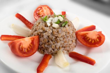 Mükemmel hizmet Buğday lapası beyaz tabakta. Rus kaşa veya pişmiş Pseudocereal Buck buğday domates, soğan ve Yeşiller ile dekore edilmiş