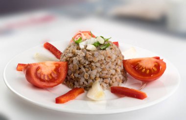 Mükemmel hizmet Buğday lapası beyaz tabakta. Rus kaşa veya pişmiş Pseudocereal Buck buğday domates, soğan ve Yeşiller ile dekore edilmiş