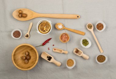 Tahta kaşıklar, çeşitli baharat ve gri kumaş arka plan düz lay ve en iyi görünümü üzerinde bütün fındık ile kompozisyon