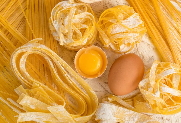 生的黄色意大利面食 Fettuccine Tagliatelle 与鸡蛋接近 鸡蛋自制面条烹饪过程 长卷通心粉 未煮熟的意大利面顶视图 — 图库照片