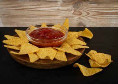 Koyu kırsal arka planda kırmızı soslu üçgen mısır cipsi. Nacho tortilla için Meksika cipsi, mısır cipsi, mısır cipsi veya klasik country tarzı soslu totopos.