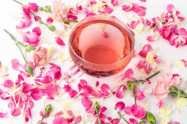 Karanfil yapraklı pembe çiçek çayı. Bahar çiçekleriyle dolu cam bardakta sıcak gül içeceği
