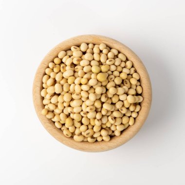 Beyaz arka plan görüntüsünde çiğ susuz soya fasulyesi. Tahta kasede kuru soya fasulyesi, yakın plan soya fasulyesi yığını.