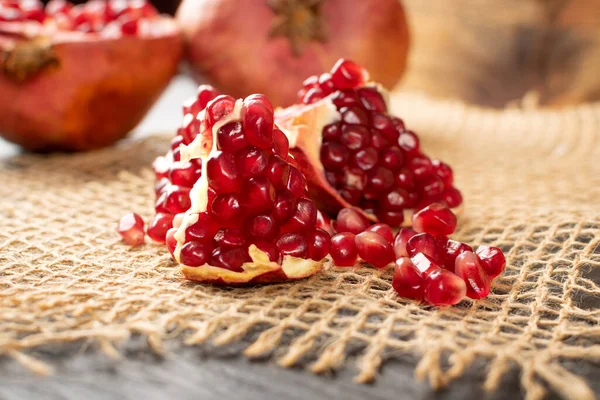 Macro Photo of Fresh Ripe Organic Pomegranate Fruit with Juicy Seeds on Rustic Tablecloth Burlap Background. Still Life in Village Style