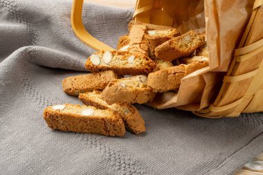 Biscotti di prato 'nun rustik masa örtüsü çuval bezi arka planı. Geleneksel İtalyan fındık kurabiyeleri. Hasır sepette bademli ev yapımı cantucci kurabiyesi.
