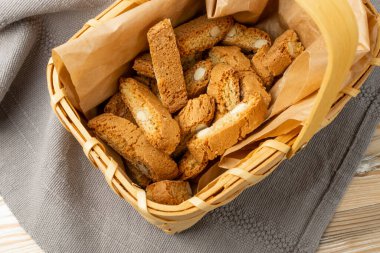 Biscotti di prato 'nun rustik masa örtüsü çuval bezi arka planı. Geleneksel İtalyan fındık kurabiyeleri. Hasır sepette bademli ev yapımı cantucci kurabiyesi.